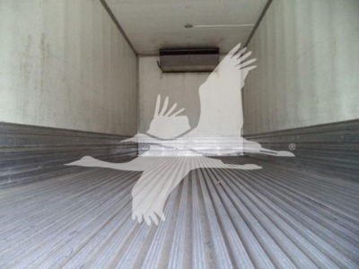 Interior of a refrigerated truck trailer showing ribbed metal floor and a rear wall with a small unit near the ceiling.