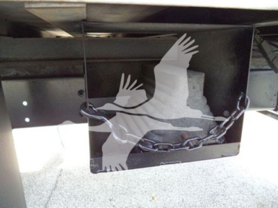 Refrigerated truck rear showing chain and metal legs with bird graphic on black plate