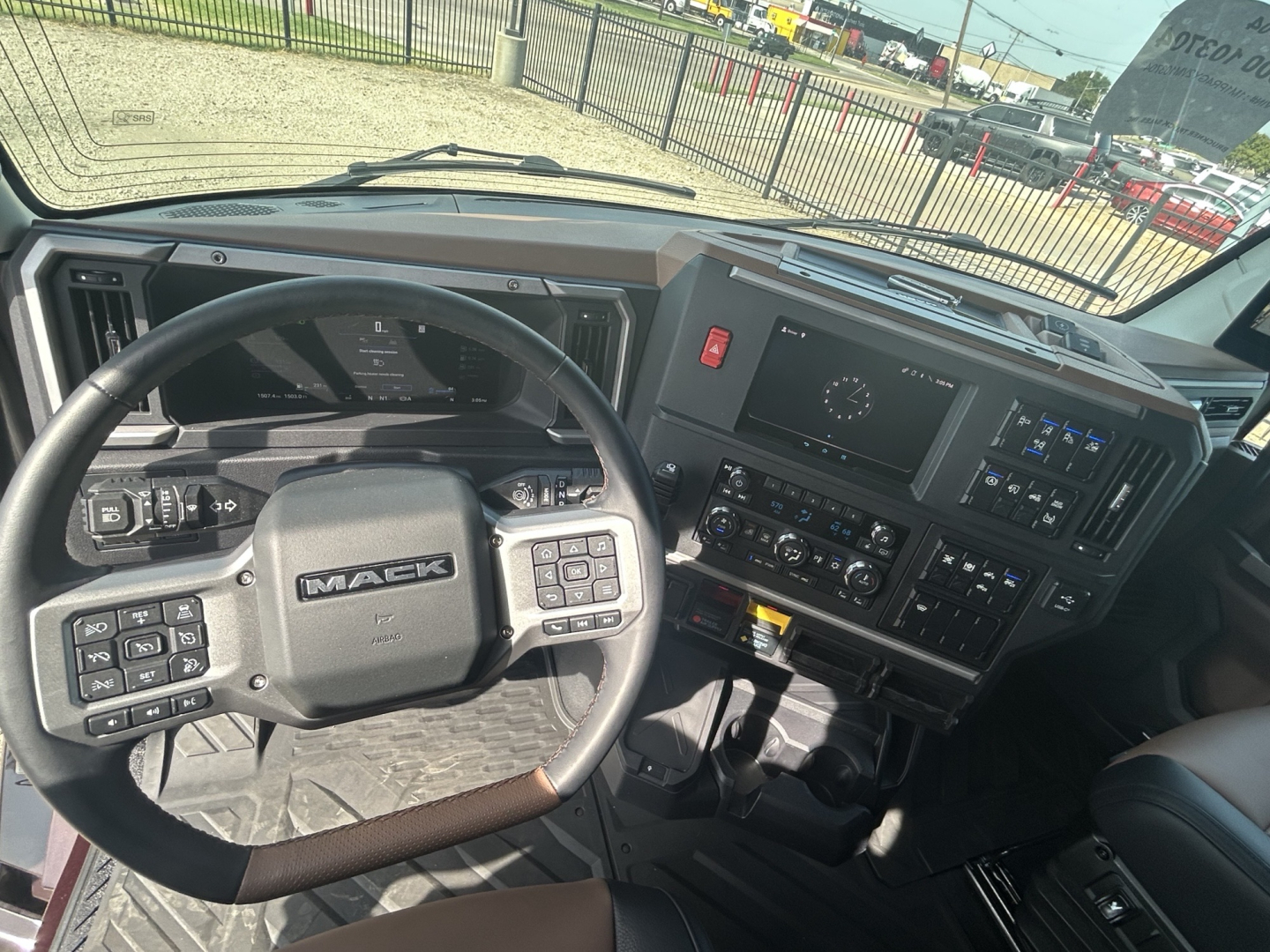 Mack PR64T76H truck interior showing steering wheel with Mack logo and dash controls, instrument cluster, infotainment screens, and center console.