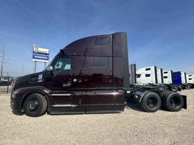 Mack PR64T76H conventional sleeper truck side view showing dark maroon cab and multiple rear axles.