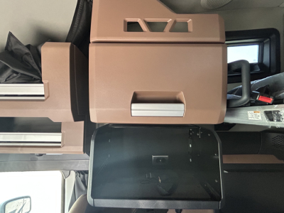 Interior of a new Mack PR64T76H truck showing sleeper cab area with tan/brown dashboard panels, overhead storage, and control panels.