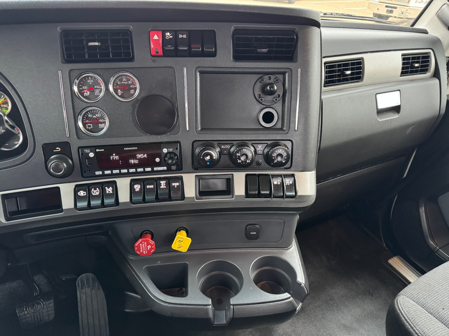 Dashboard of a Kenworth T680 cabin showing instrument cluster, climate controls, and auxiliary switches; visible text includes various gauges and control labels.