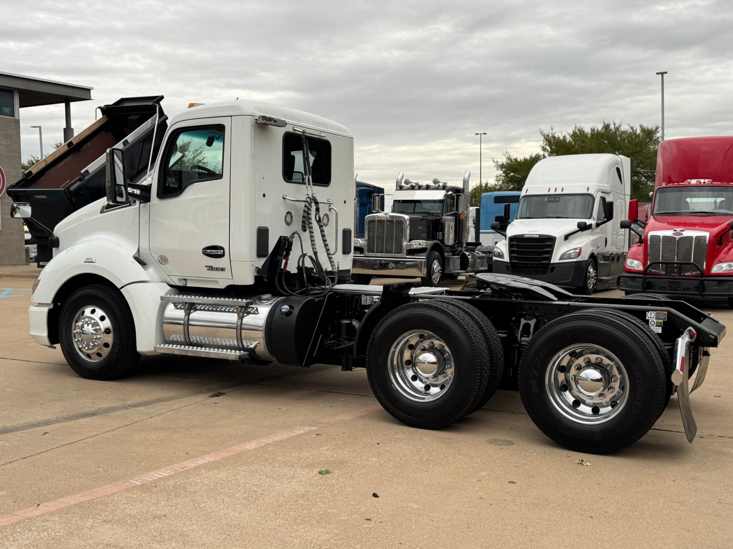 Kenworth T680 daycab in-service showing side cab with chrome fuel tanks and dual rear axles, view of truck bed and wheel configuration.