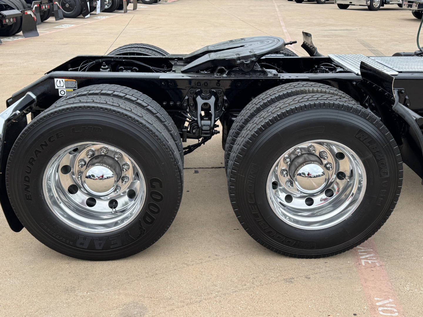 Kenworth T680 chassis showing dual rear tandem wheels with Goodyear Endurance tires and chrome hubcaps, undercarriage frame rail and fifth wheel mounting area visible.