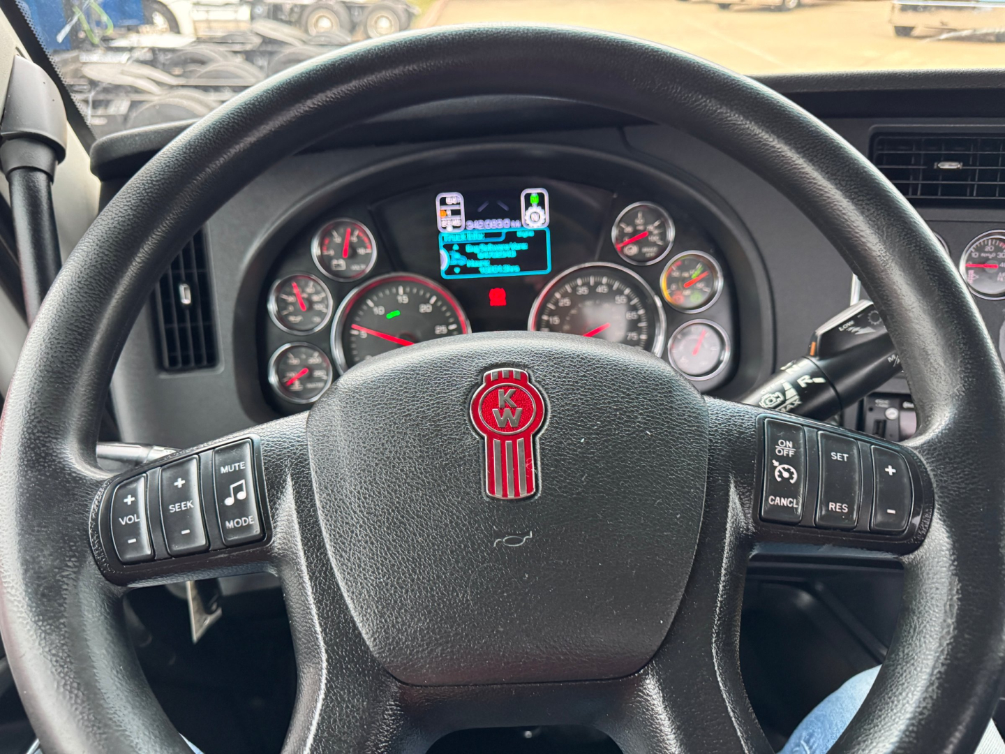 Kenworth T680 steering wheel and instrument cluster view in cab showing gauges and multifunction controls.