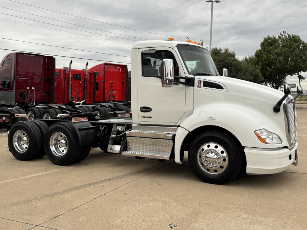 Kenworth T680 conventional daycab truck side view showing front grille, white cab, chrome mirrors, and dual rear axles with aluminum fuel tanks.