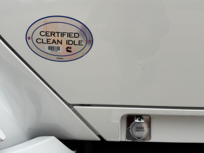 Kenworth T680 engine bay area showing Certified Clean Idle badge and engine heater plug cover on rear side panel.
