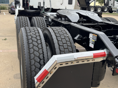 Kenworth T680 chassis showing dual rear axles and heavy-duty tires with tread pattern; visible fender steps and frame rails with warning labels
