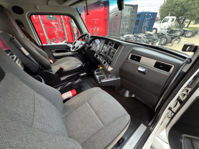 Truck cab interior of a 2022 Kenworth T680 showing driver seat, steering wheel, dashboard, and center console with controls.