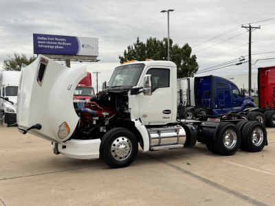 Kenworth T680 tractor cab with hood open showing engine bay and front fender, white exterior, on a lot.