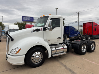 Kenworth T680 truck with white cab, side view showing chrome fuel tanks, steps, and dual rear axles. Visible text on cab includes Kenworth badge and exhaust.