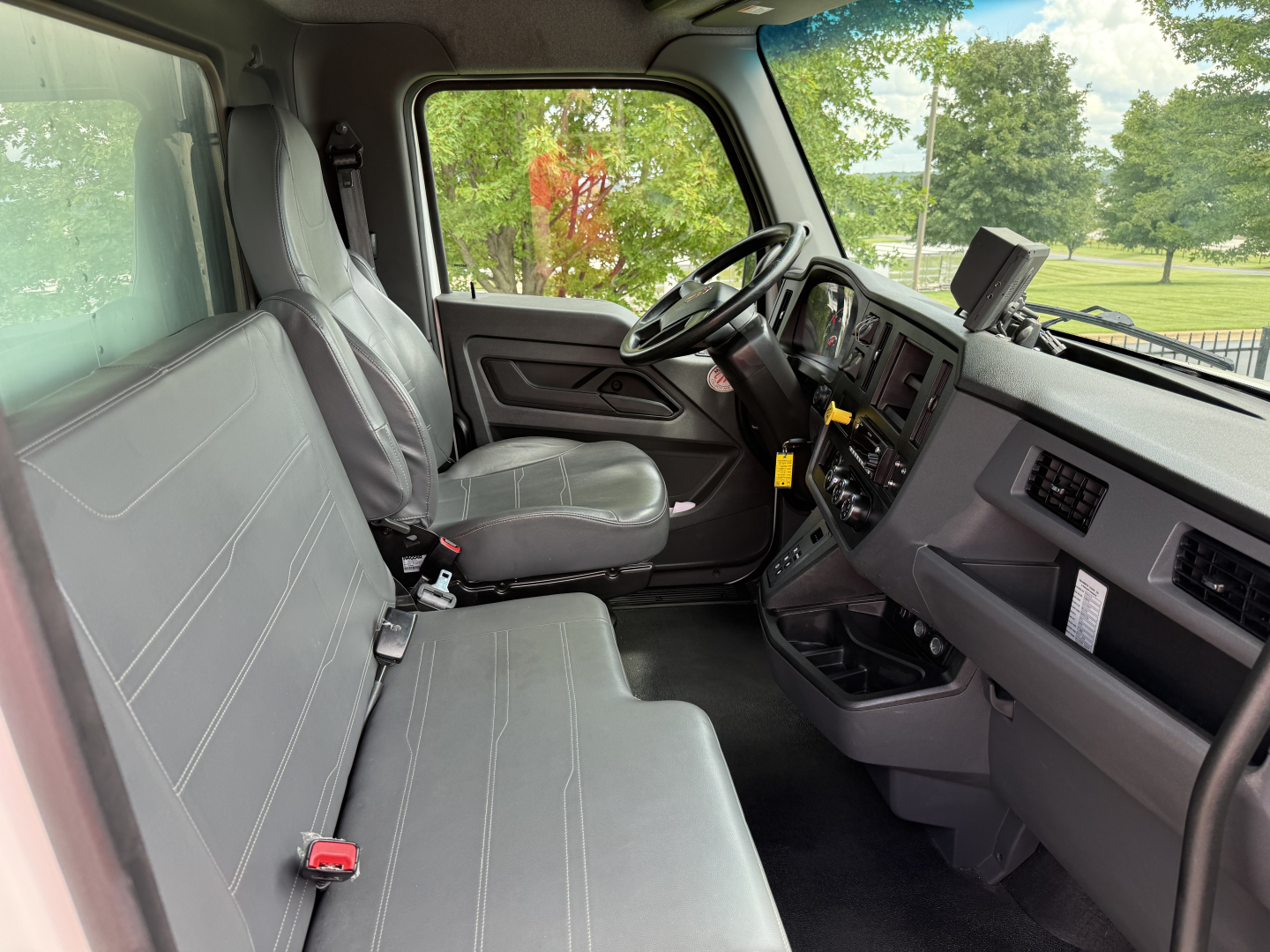 Kenworth T380 cab interior showing front bench seat and dashboard with steering wheel, gauges, and center console.