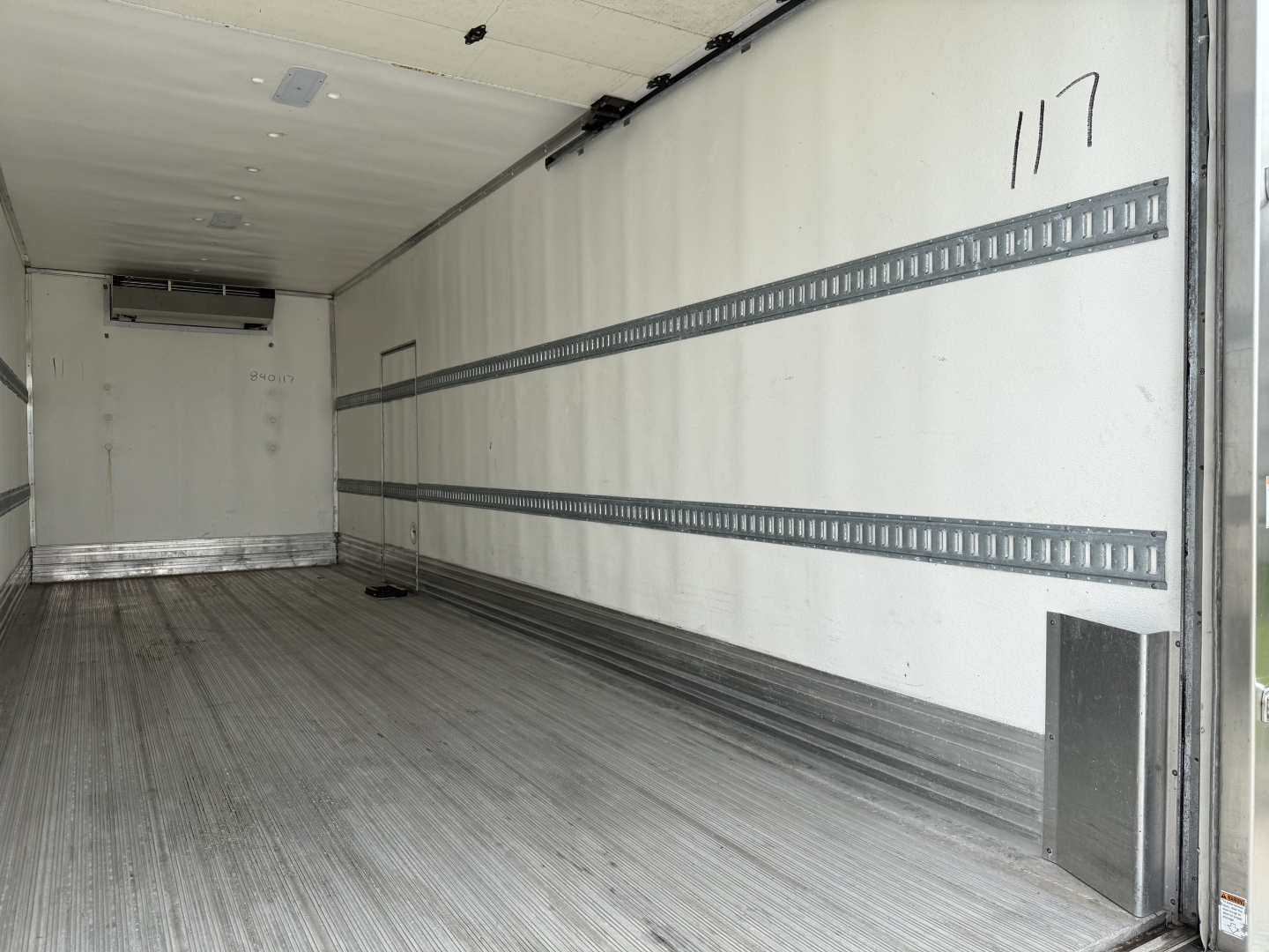 Refrigerated truck cargo area of a 2023 Kenworth T380 showing empty interior with aluminum floor, wall rails, and rear doors.