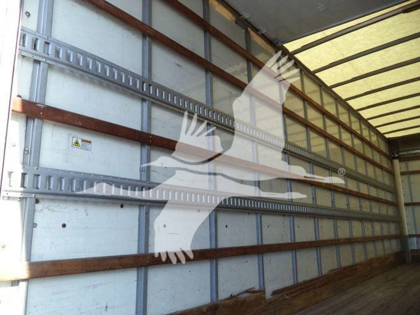 Inside of a Hino 268A box truck trailer showing metal side walls with wooden rails and wheel well area.