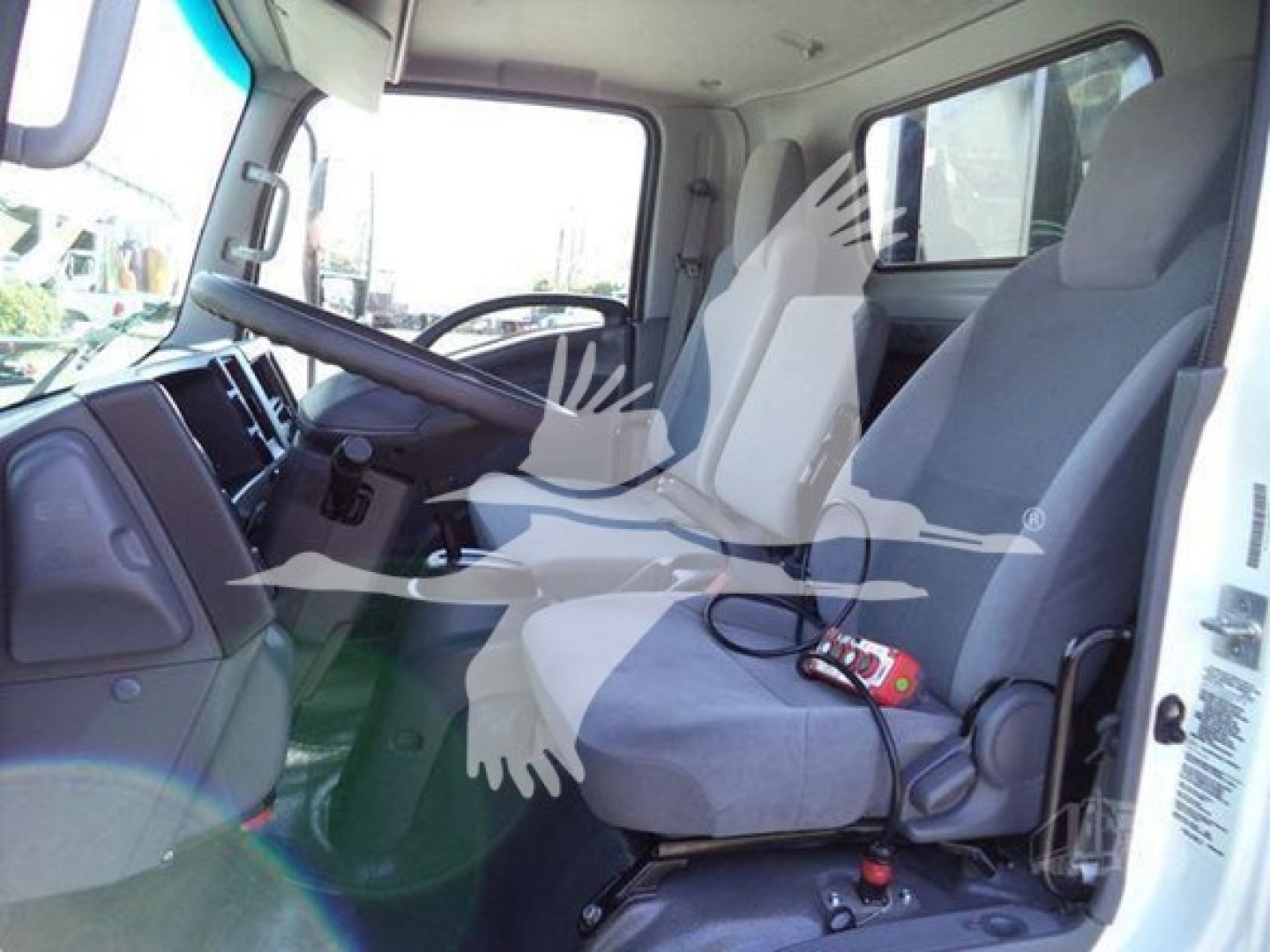 Isuzu NRR truck cab interior showing front seat and passenger seat with steering wheel, dashboard, and door frame.