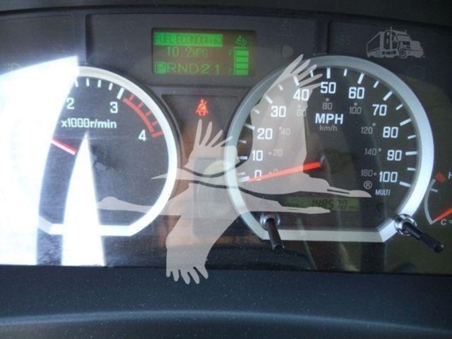 Isuzu NRR instrument cluster showing tachometer and speedometer with digital display; visible text includes BRND21, FUEL ECON, 0.2? and warning icons