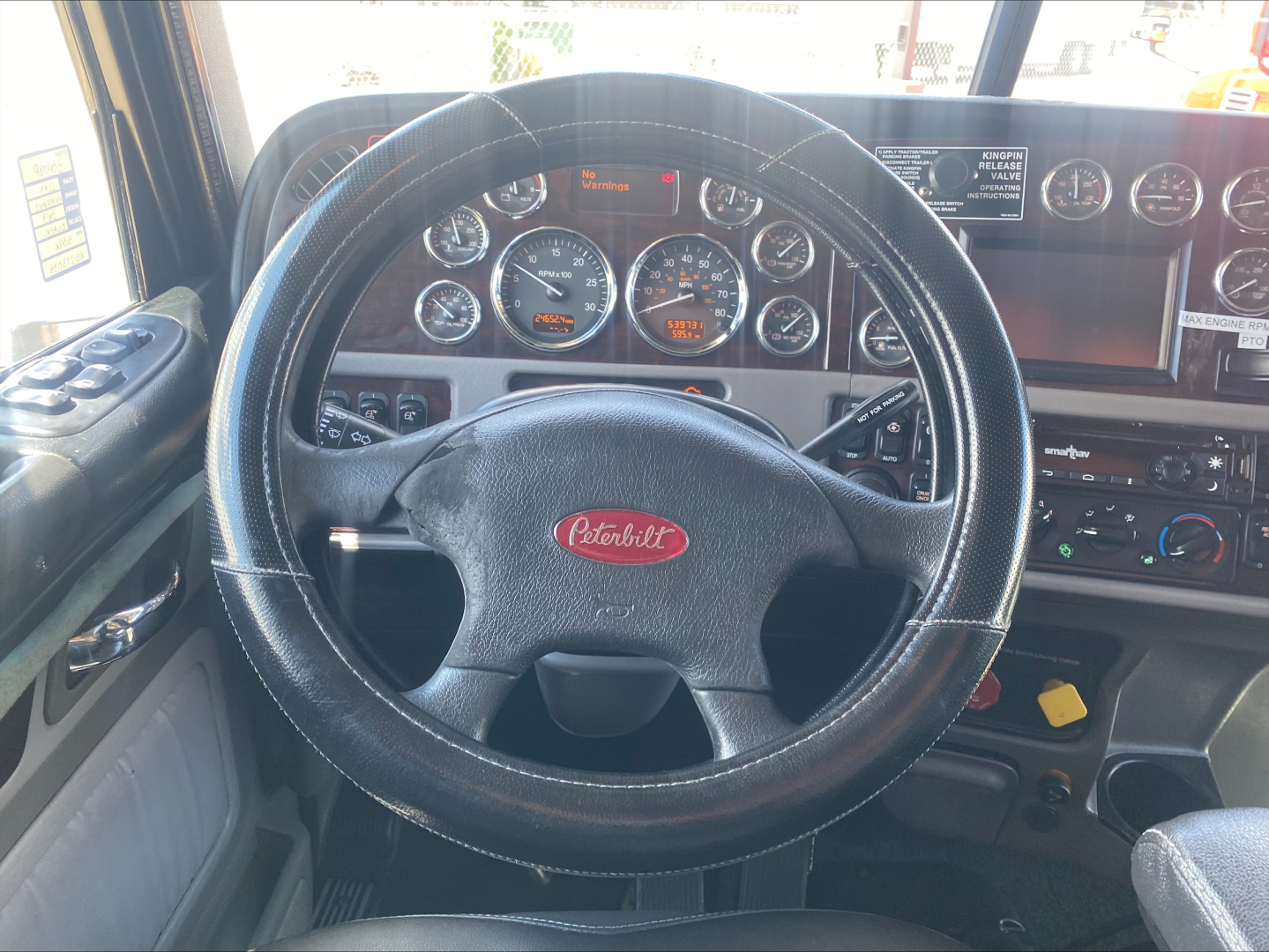 Peterbilt 389 truck interior showing steering wheel and dashboard with multiple gauges and control panels.