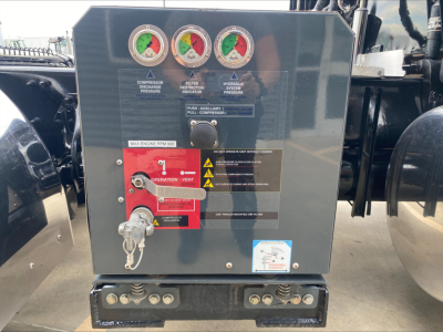 Peterbilt 389 engine bay control panel with gauges and red lever, vents, and label stickers in view.