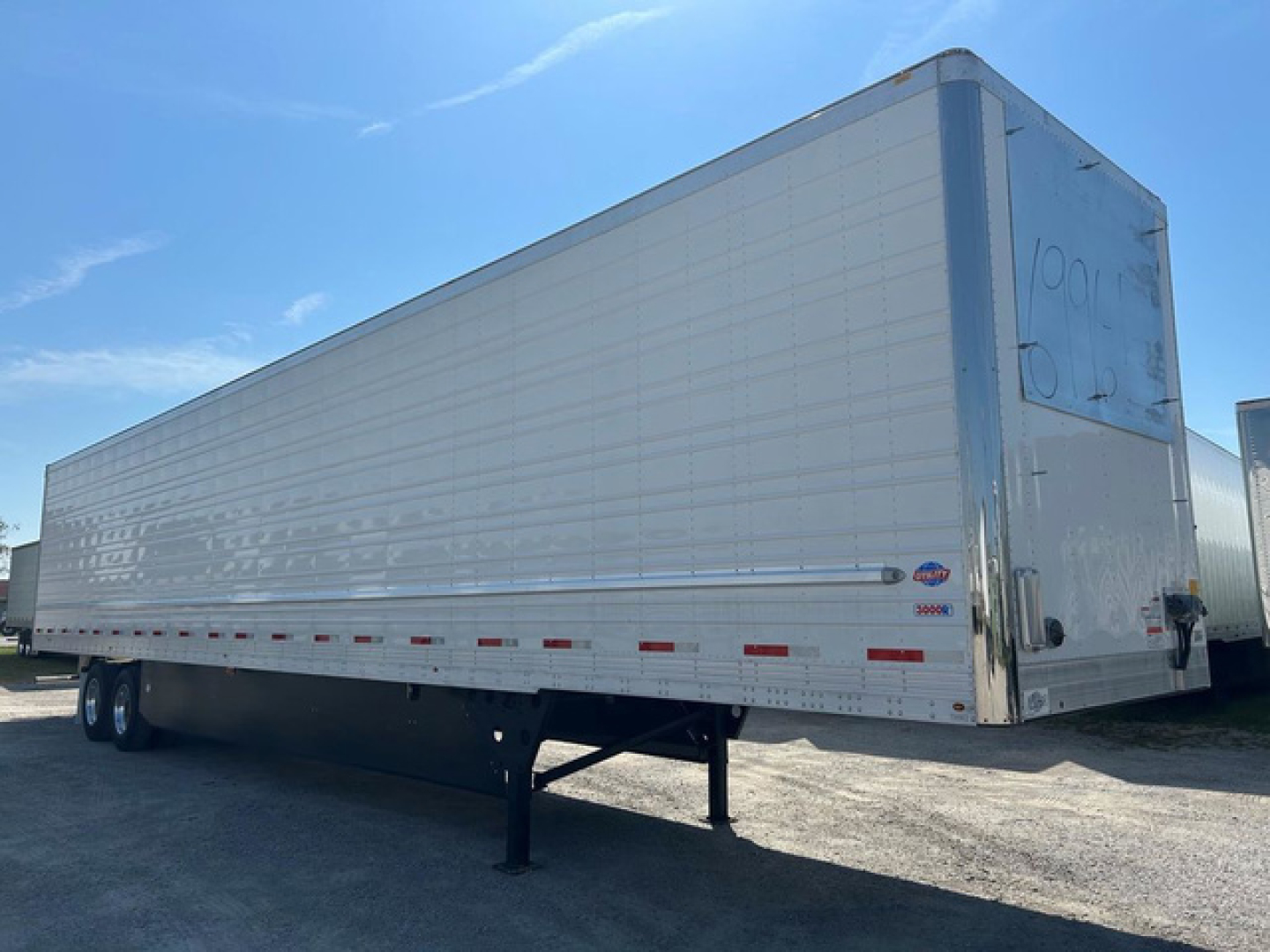 Trailer side and rear view showing a 2027 Utility reefer trailer with metal corrugated sides, rear doors, and landing gear visible.