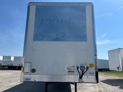 Reefer trailer rear view showing plain white doors with a large faded grey/blue rectangle at top and handwritten numbers on it. Rear bumper and electrical box visible.