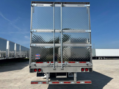 Rear view of a 2027 Utility reefer trailer showing diamond plate doors, metal frame, and rear lighting with a small utility sticker.