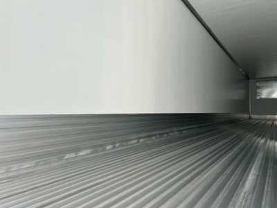 Interior of a refrigerated trailer cargo area with ribbed metal floor and side walls, empty and clean.