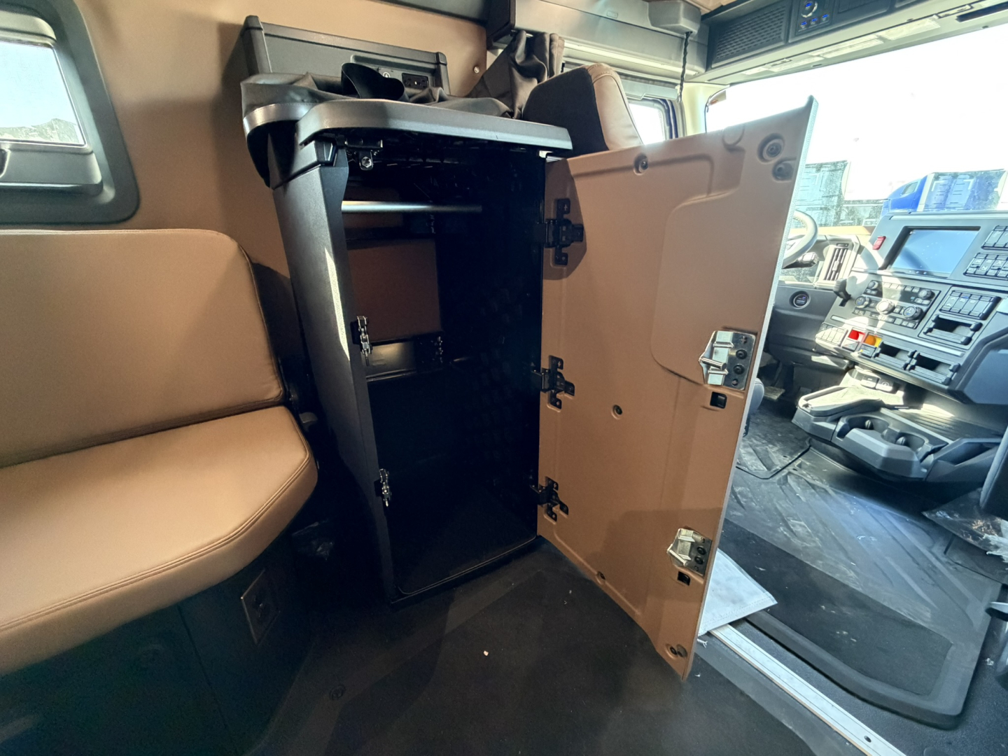 Cabin interior of a new 2026 Mack PR64T76H showing an open overhead cabinet and entry area near the driver seat.