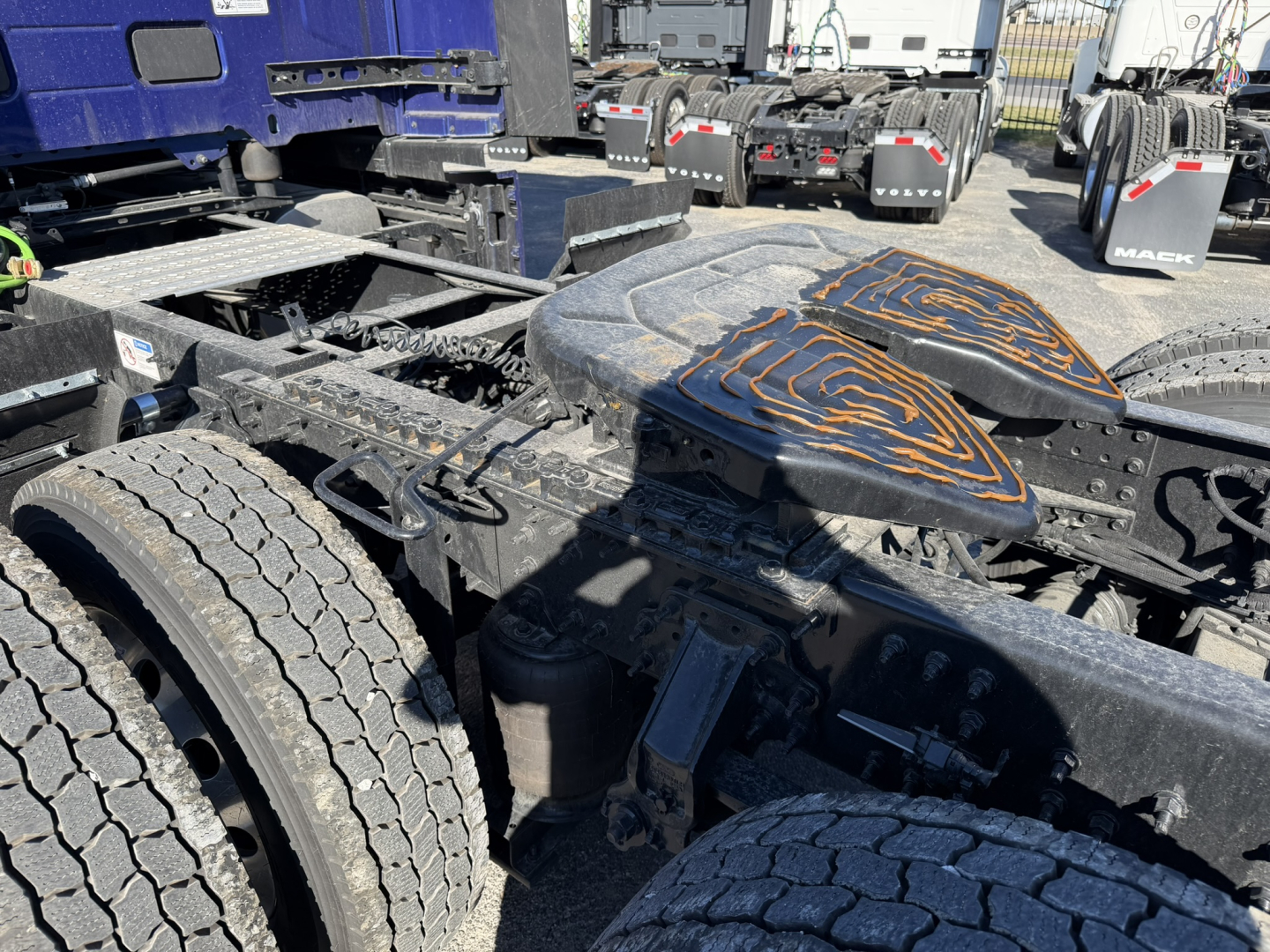 Base view of a 2026 Mack PR64T76H truck chassis showing dual rear wheels and fifth-wheel/kingpin area with deck plates and fuel/tank components.