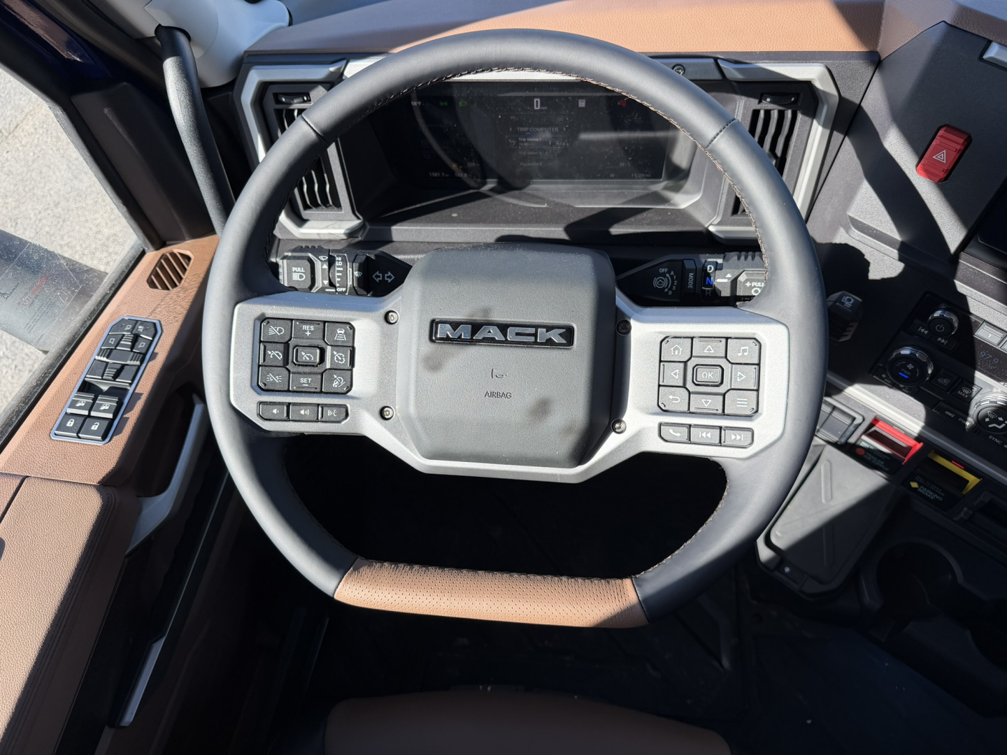 Mack PR64T76H truck steering wheel and dashboard seen from driver seat showing Mack logo and control panels.