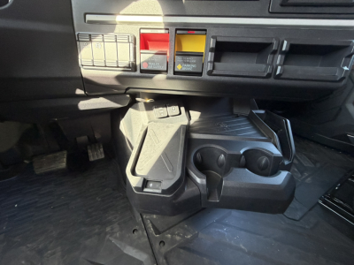 Mack PR64T76H truck interior center console area with cup holders and controls, dashboard switches, and pedals visible