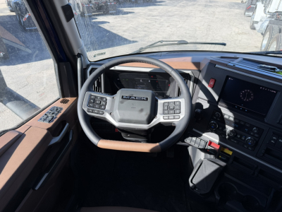 Mack truck steering wheel and dashboard interior with controls, brown trim, and digital display.