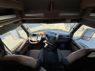 Mack PR64T76H truck interior cab view from front seats showing dashboard and steering wheel with overhead compartments.