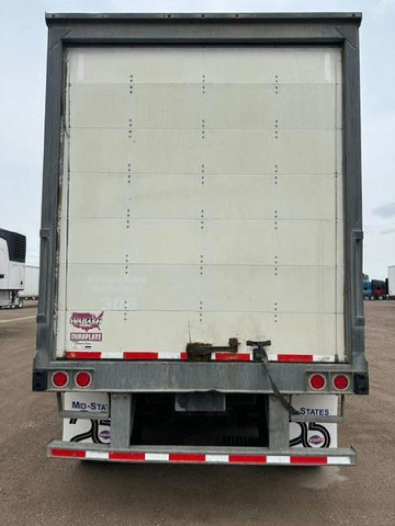 Trailer rear showing roll-up van doors and bumper with lights and license plate mounts.