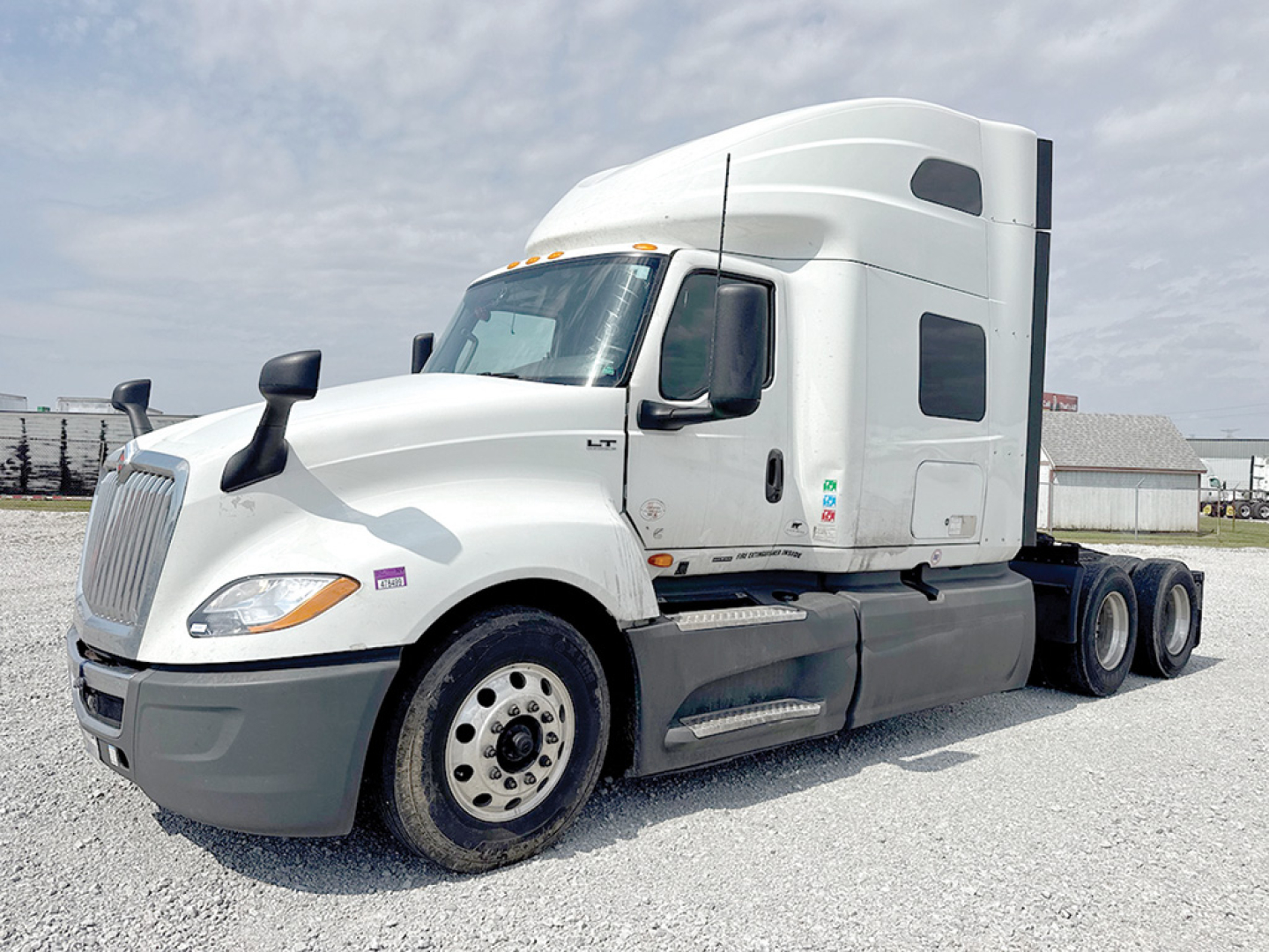 Truck with sleeper cab showing International LT badge and side fuel tanks. Front wheel and white exterior with black chassis. No text visible except generic truck features.