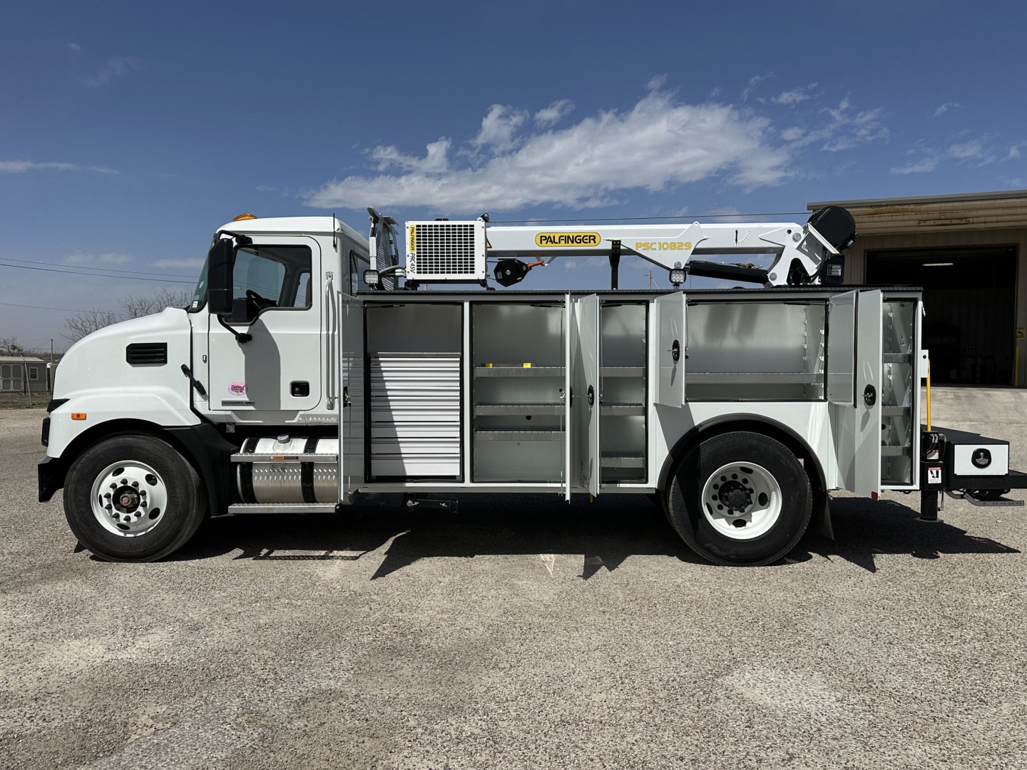 Service/Utility truck side view showing ladder rack and storage compartments on a 2025 Mack MD7 with Aerials and tool box.