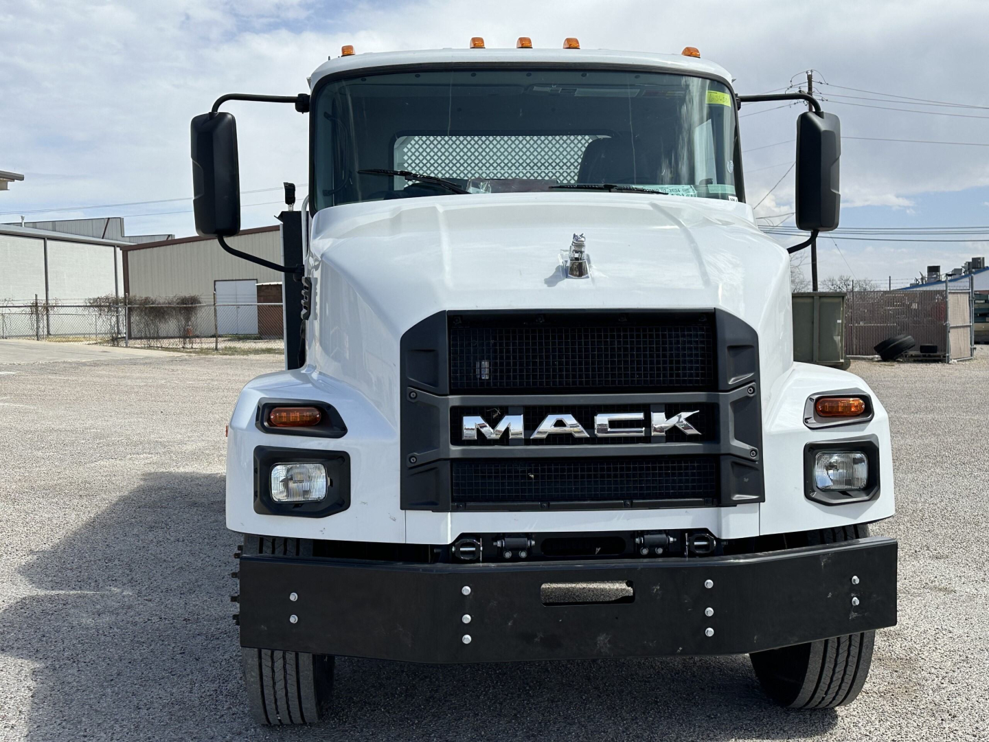 Front view of a white 2025 Mack MD7 service truck showing bold grille with MACK logo and black front bumper.