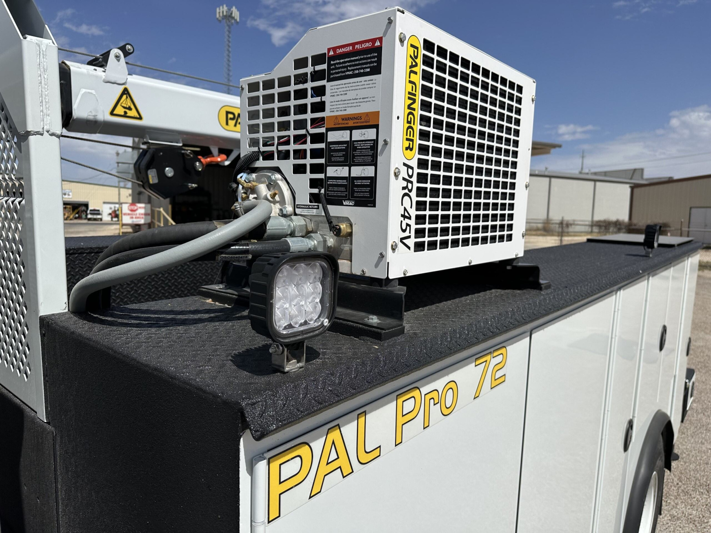 Mack MD7 service/utility truck body with portable Pal Pro 72 unit and Palfinger label showing radiation-style warning, LED work light, various hoses and brackets.