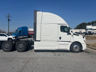 Freightliner Cascadia 126 tractor cab side view showing sleeper area and front wheel; white truck in a dealership lot.