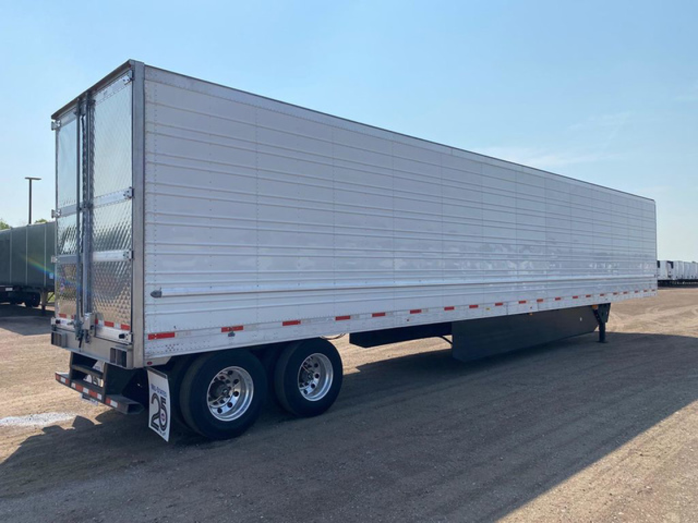 Trailer side view showing aluminum refrigerated box with dual rear axles and rear doors.