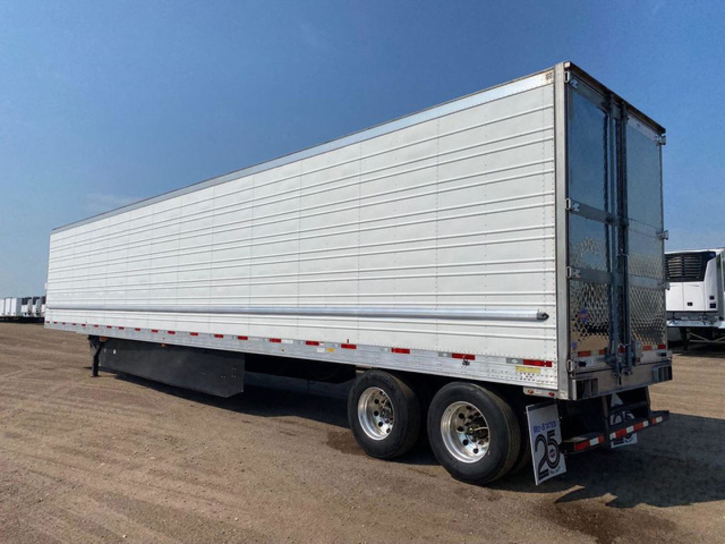 Trailer side view of a 2021 Utility reefer with silver dry van body, two-axle configuration, rear cargo doors, and wheel tracks visible.