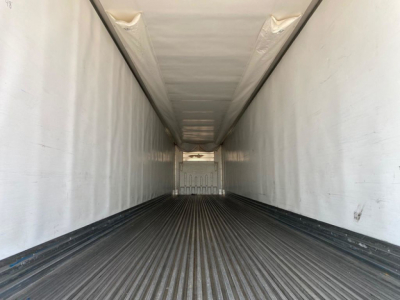 Trailer interior showing empty refrigerated cargo area with ribbed floor and white walls.