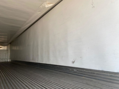 Refrigerated trailer interior side wall and ribbed floor showing smooth metal surface and white walls.