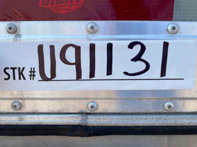 Stock number plate reading STK # U91131 on a trailer rear with metal frame and rivets.