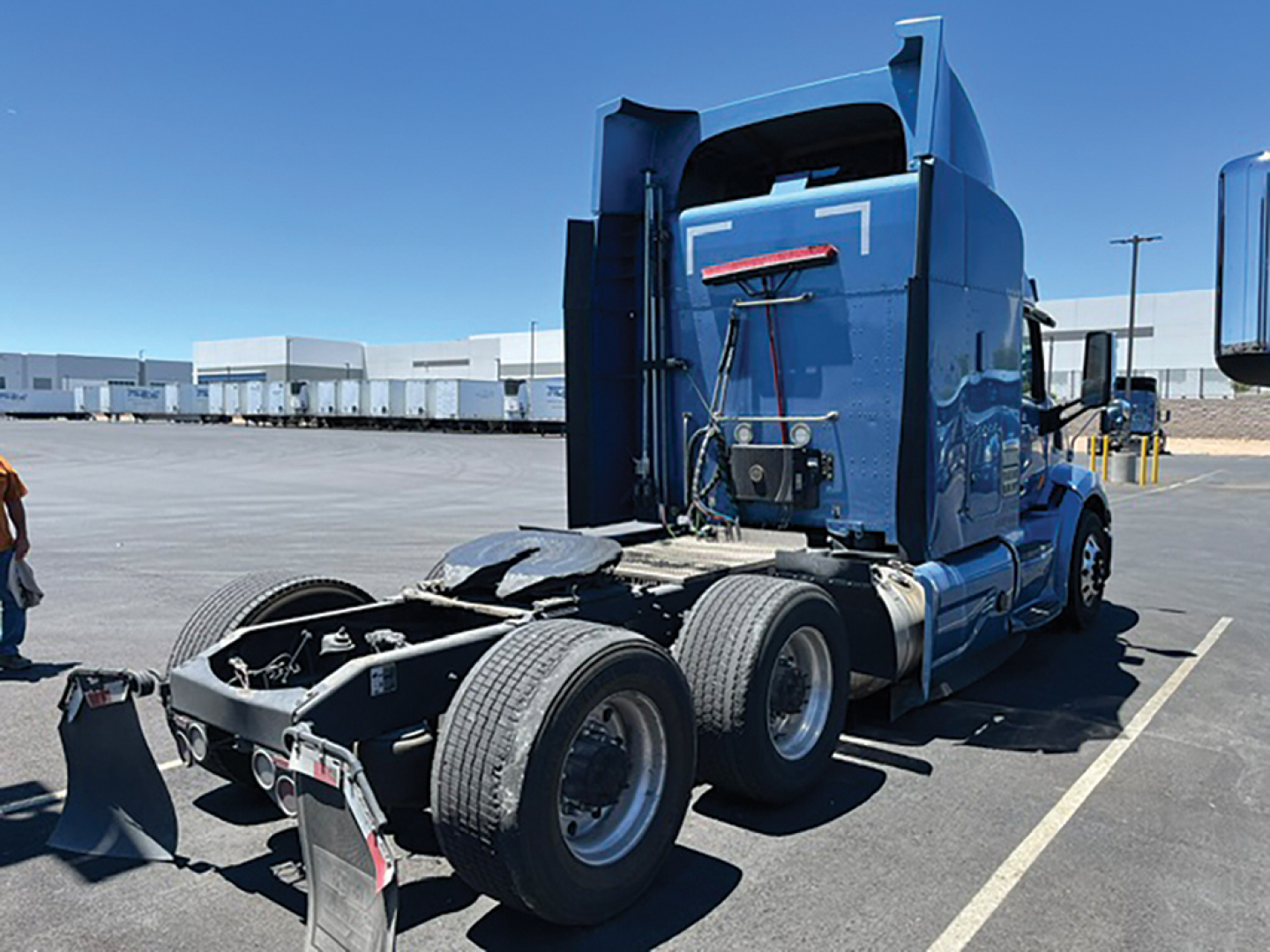 Peterbilt 579 UltraCab tractor rear and drivetrain showing dual rear axles and fifth wheel in a truck lot.
