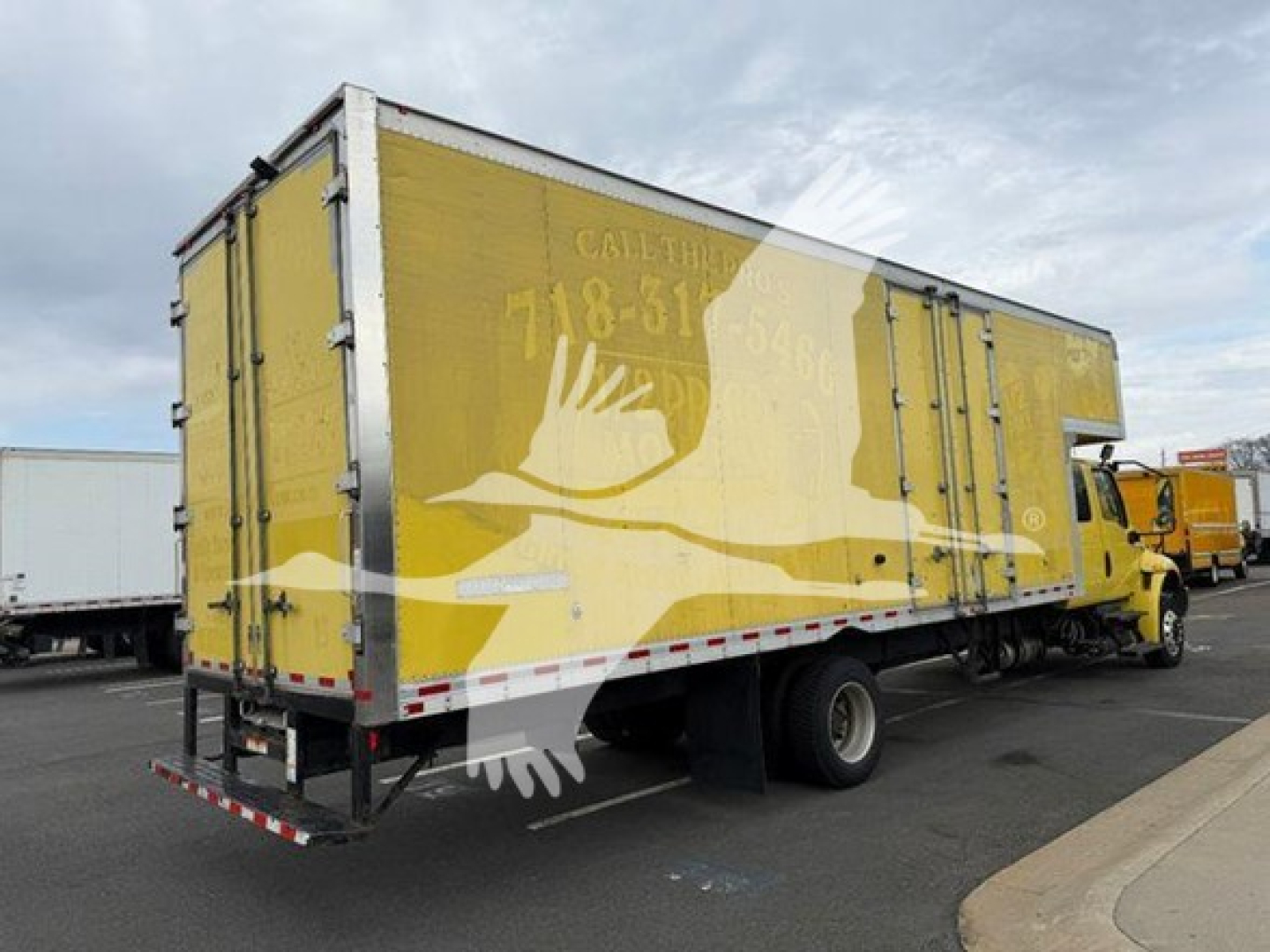 Truck box side view showing yellow moving van with graphic bird design and rear underride guard.