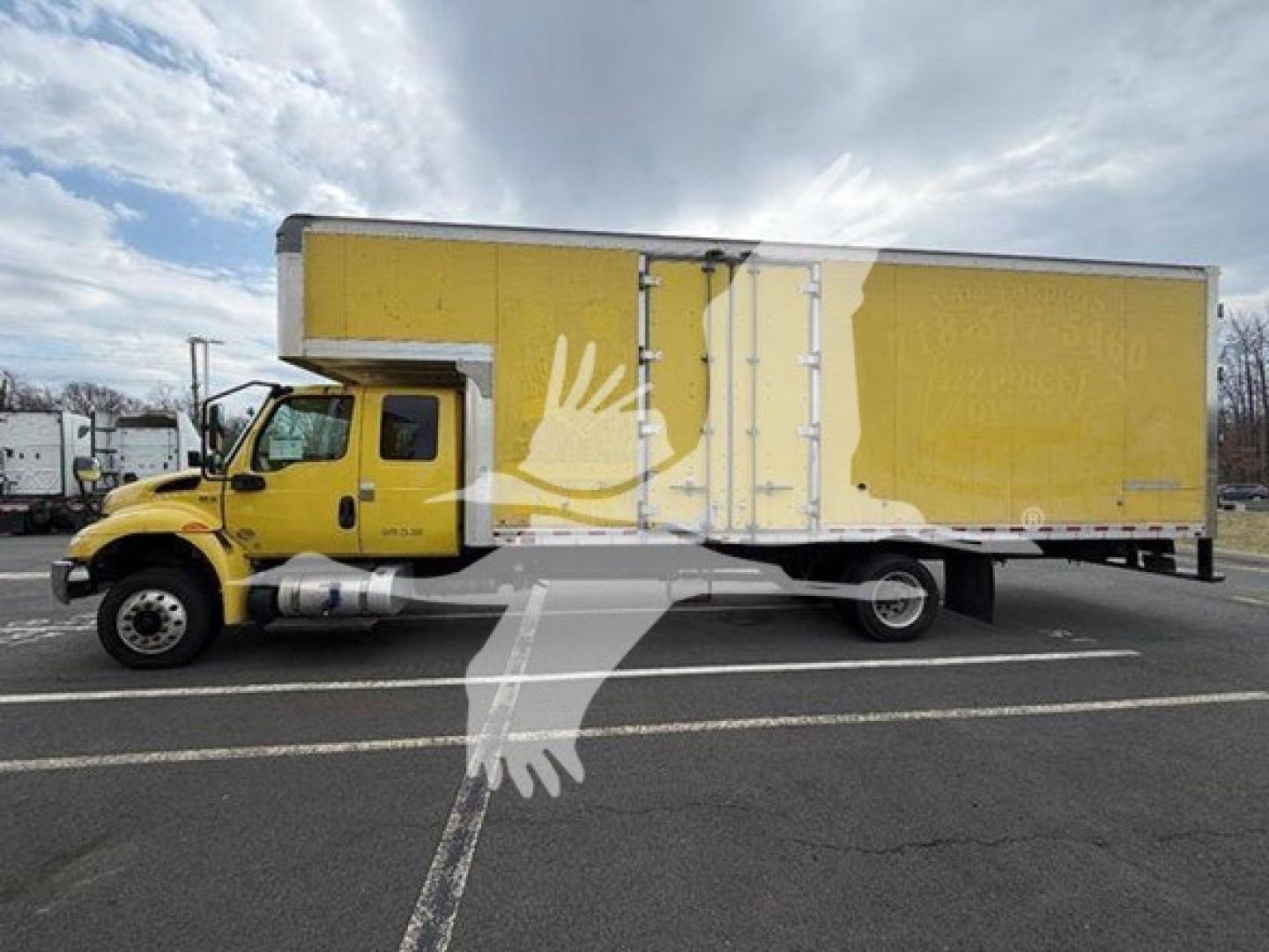 Truck side view showing large yellow moving van with white graphic on cargo area and black wheels.