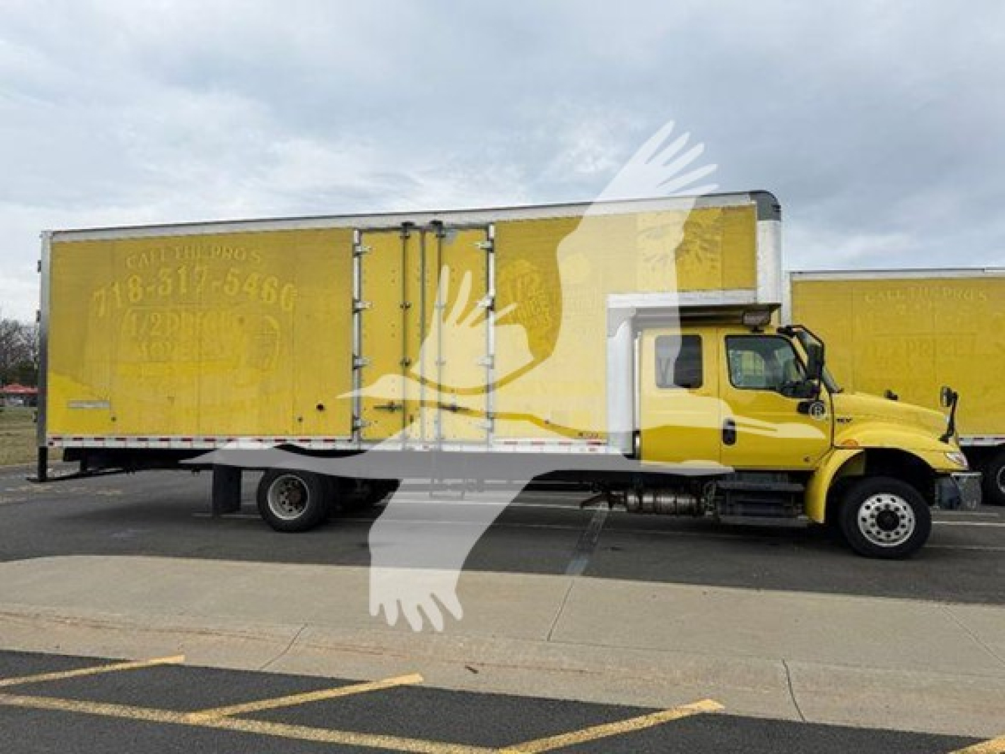 Truck side view of a yellow moving van with a large box trailer and cab in foreground.