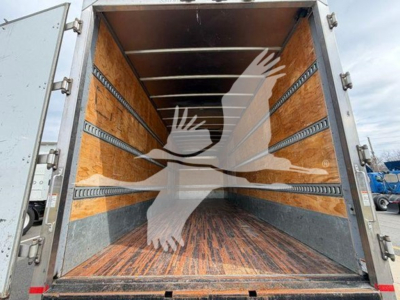 In-service moving van cargo area showing wooden interior walls and tiedown rails.