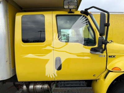 Yellow 2020 International MV moving van cab side with MV logo, window, mirror, and door handle visible.
