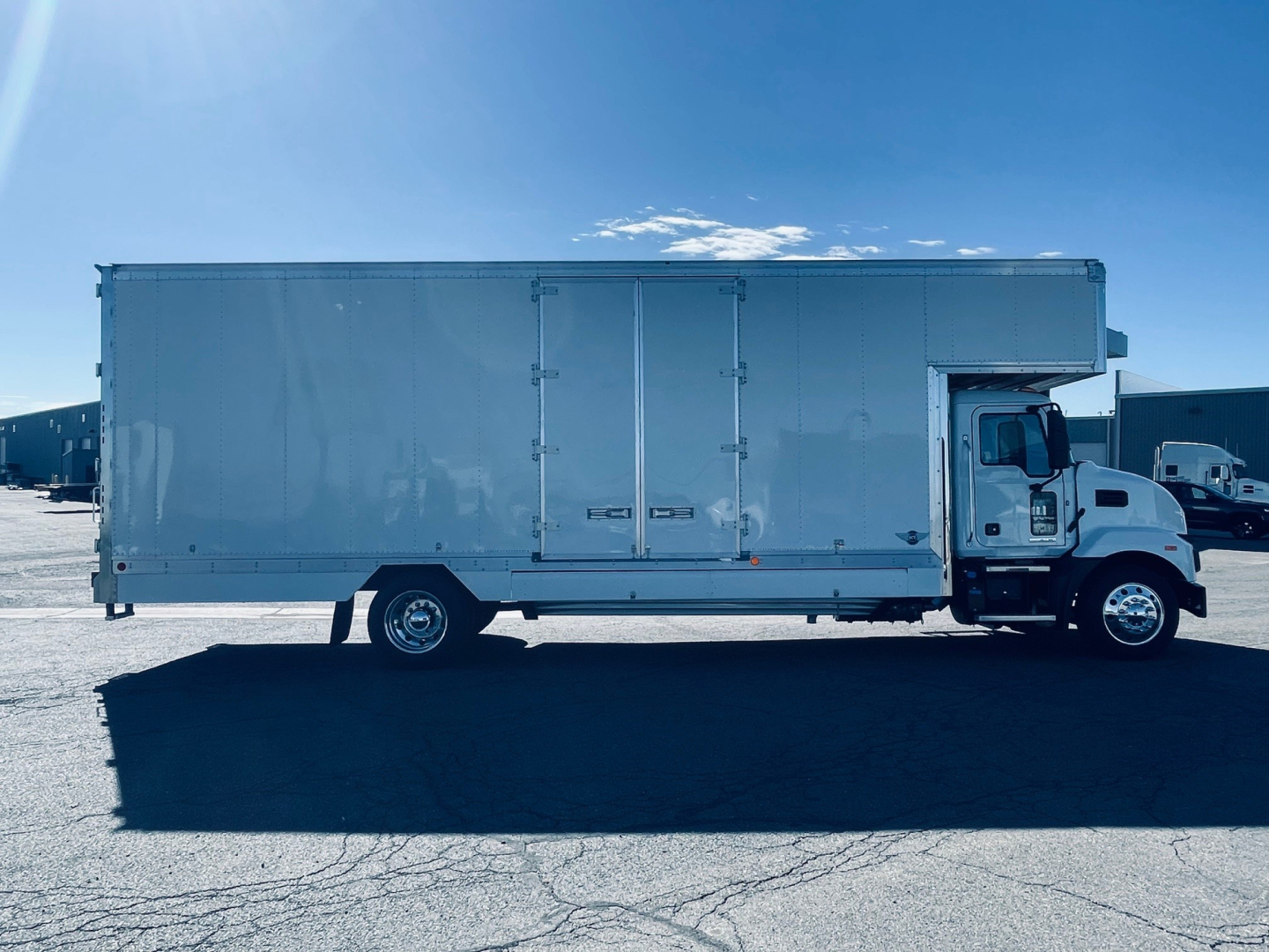 Box truck side view showing large cargo box with rear double doors on a Mack MD6 chassis.